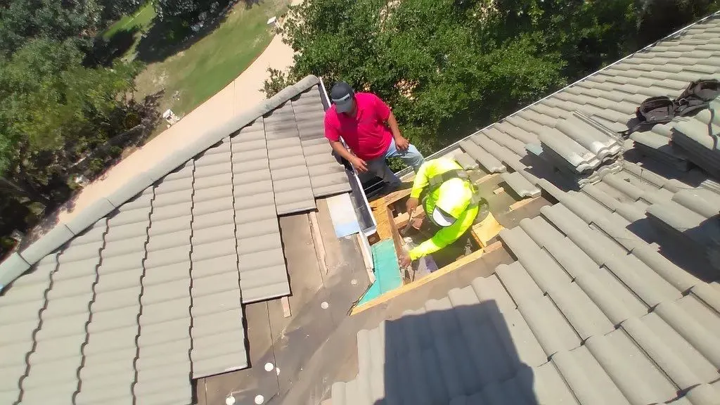 Roofing contractors replacing damaged wood decking and underlayment during a targeted residential tile roof leak repair